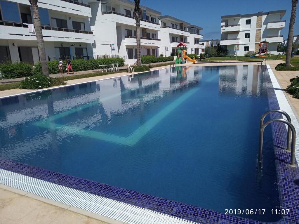 une grande piscine bleue en face d'un bâtiment dans l'établissement marbella beach, à Minaret de Mansuria