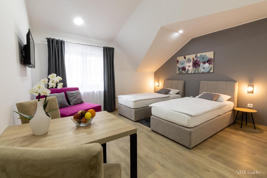 a living room with two beds and a table at Apartmani Gundulić in Osijek