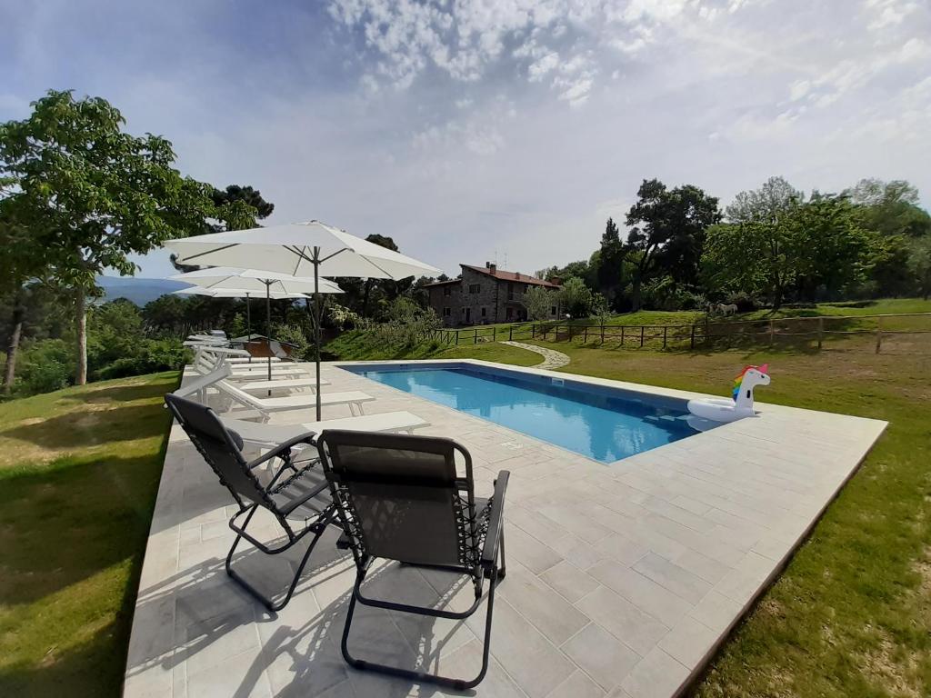 a swimming pool with two chairs and an umbrella at Casolare Giovangrande in Poppi