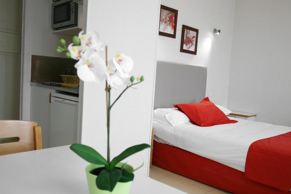 a bedroom with a bed and a table with a plant at Résidences Guerlin in Toulouse