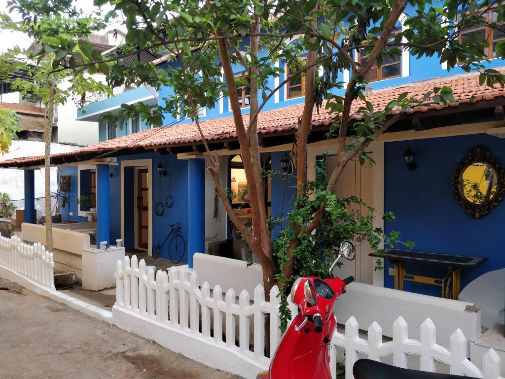 une maison bleue avec une clôture blanche et un scooter rouge dans l'établissement The White Balcao, à Panaji