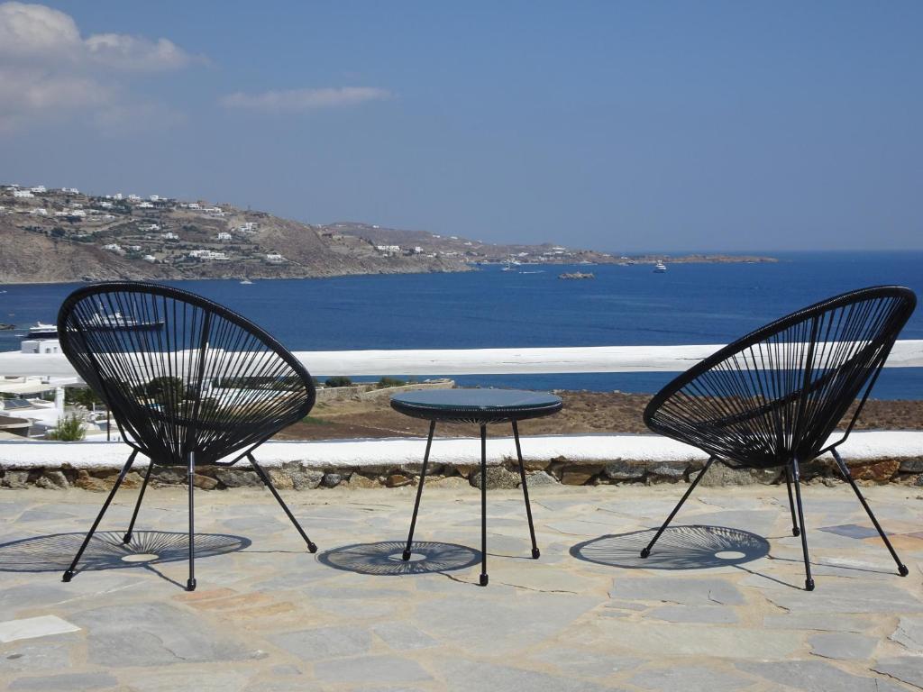 two chairs and a table on a patio with the ocean at enJOY the sea and relax in Mikonos