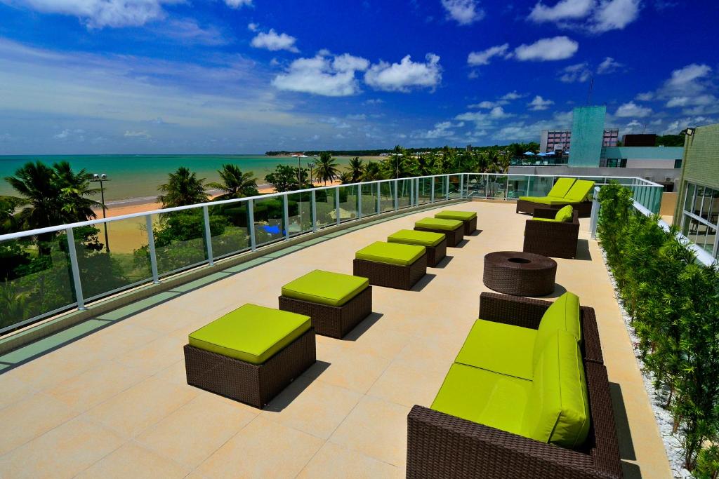 una fila de bancos en un balcón con vistas a la playa en Nord Luxxor Cabo Branco, en João Pessoa