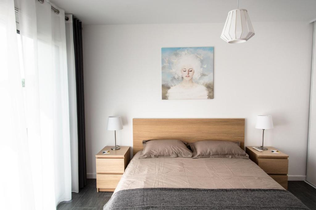 une chambre avec un grand lit avec deux tables de nuit dans l'établissement Studio indépendant chez l’habitant au calme, à Dompierre-sur-Yon