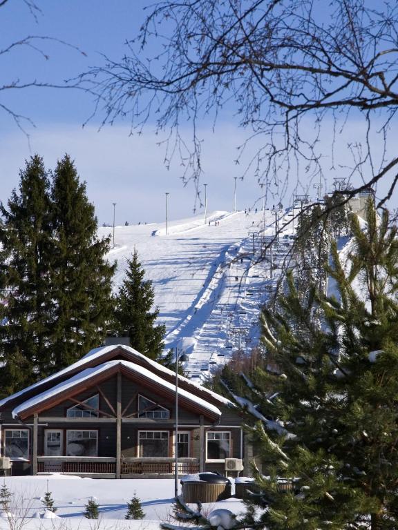 a ski lodge with a snow covered mountain in the background at Himoshovi Cottages in Jämsä