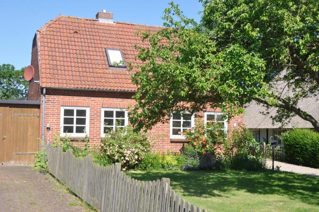 une maison en briques avec une clôture devant elle dans l'établissement Fischerhus, à Fehmarn