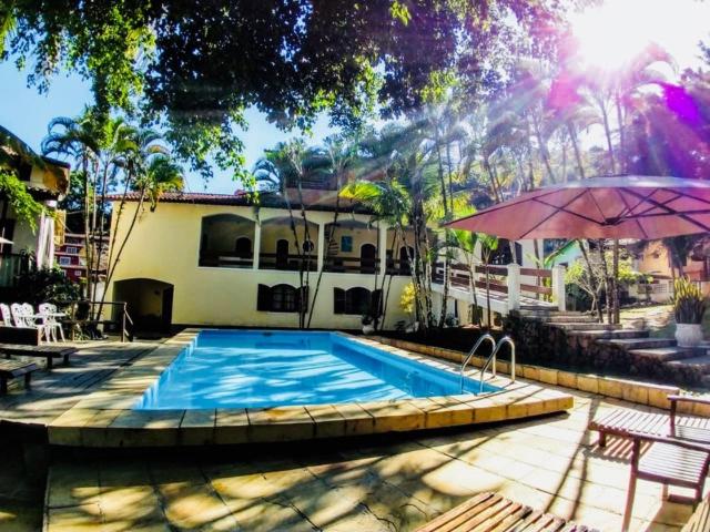 uma piscina com um guarda-sol ao lado de uma casa em ILHABEACH Suítes e Chalés em Ilhabela