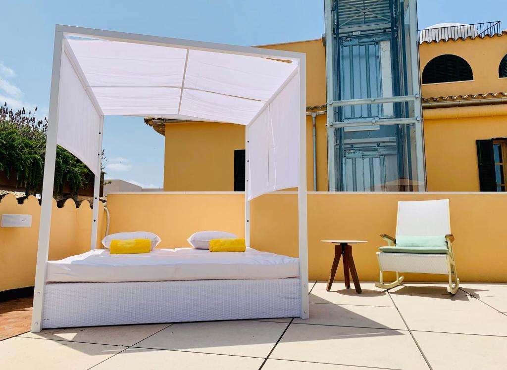 ein weißes Himmelbett und ein Stuhl auf einer Terrasse in der Unterkunft Fonda Llabres Boutique in Alcúdia