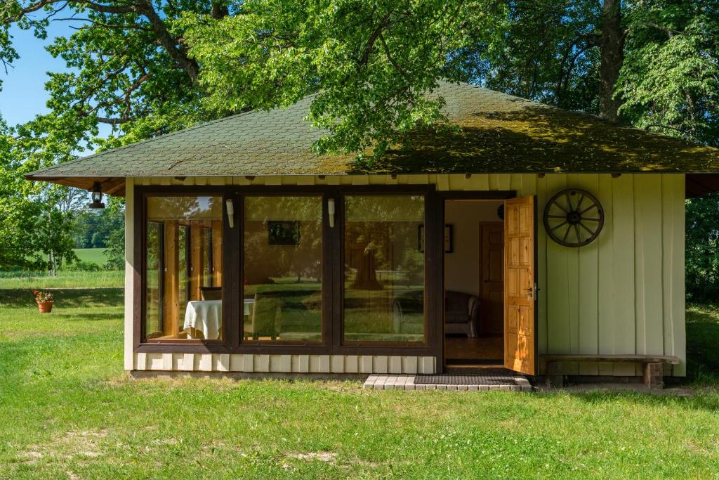 a small shed with glass doors in the grass at Rūnēnu tējas namiņš in Vidzeme