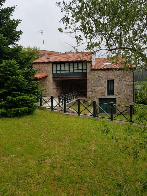 a brick house with a wooden fence in a field at Casa de Lela in Negreira