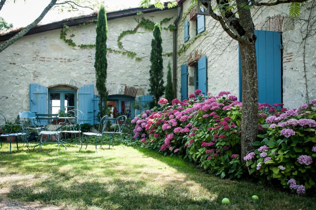 une maison avec des fleurs, des tables et des chaises dans l'établissement Les Huguets, à Villeneuve-sur-Lot