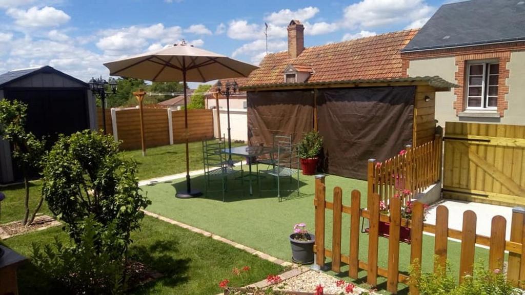 une arrière-cour avec une table et un parasol dans l'établissement Charmante maison Solognote rénovée, à La Ferté-Saint-Aubin