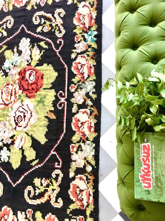 a rug on a couch next to a plant at Sato Design Hotel in Çeşme