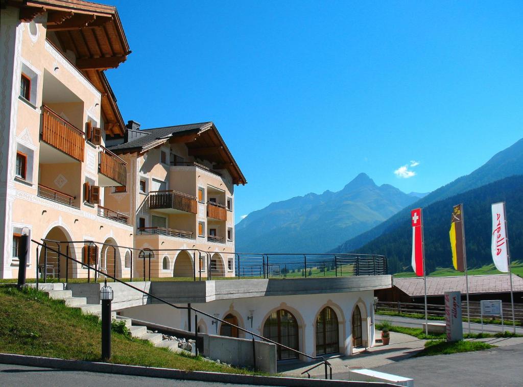 un grand bâtiment avec des montagnes en arrière-plan dans l'établissement Hotel Allegra, à Zuoz