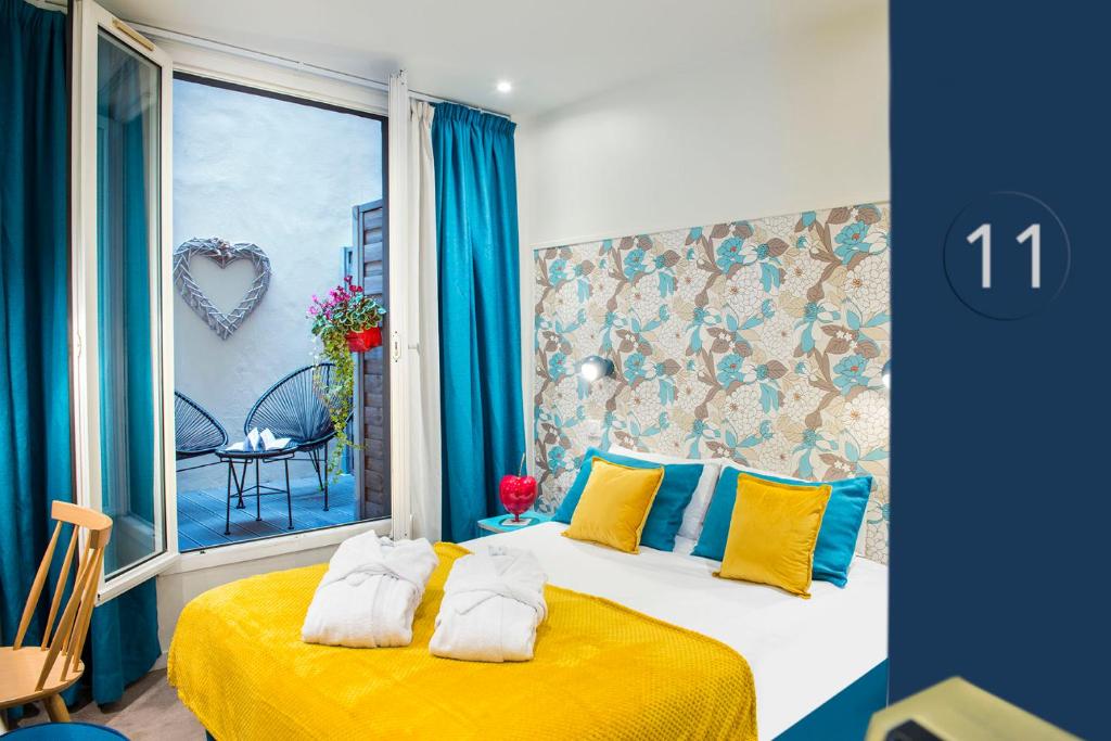 een slaapkamer met een bed met gele en blauwe kussens bij Hôtel Villa Bohème in Parijs