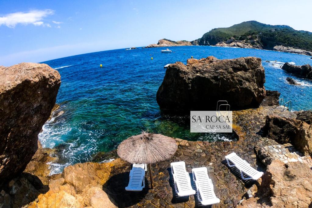 - une plage avec des chaises, un parasol et l'océan dans l'établissement Cap Sa Sal - Sa Roca 1 - Studio acceso directo al mar, à Begur