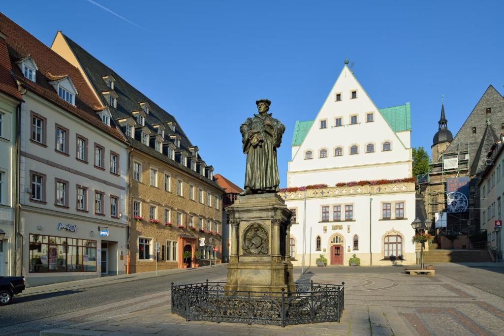 a statue in the middle of a street with buildings at Hotel Graf von Mansfeld in Lutherstadt Eisleben