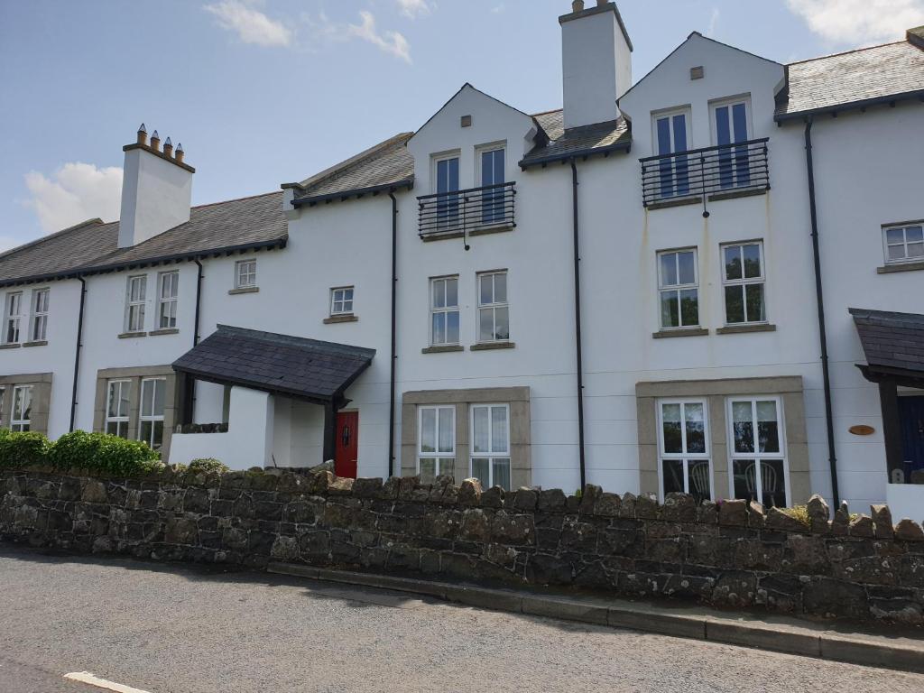 a row of white houses behind a stone wall at Coastal View in Bushmills