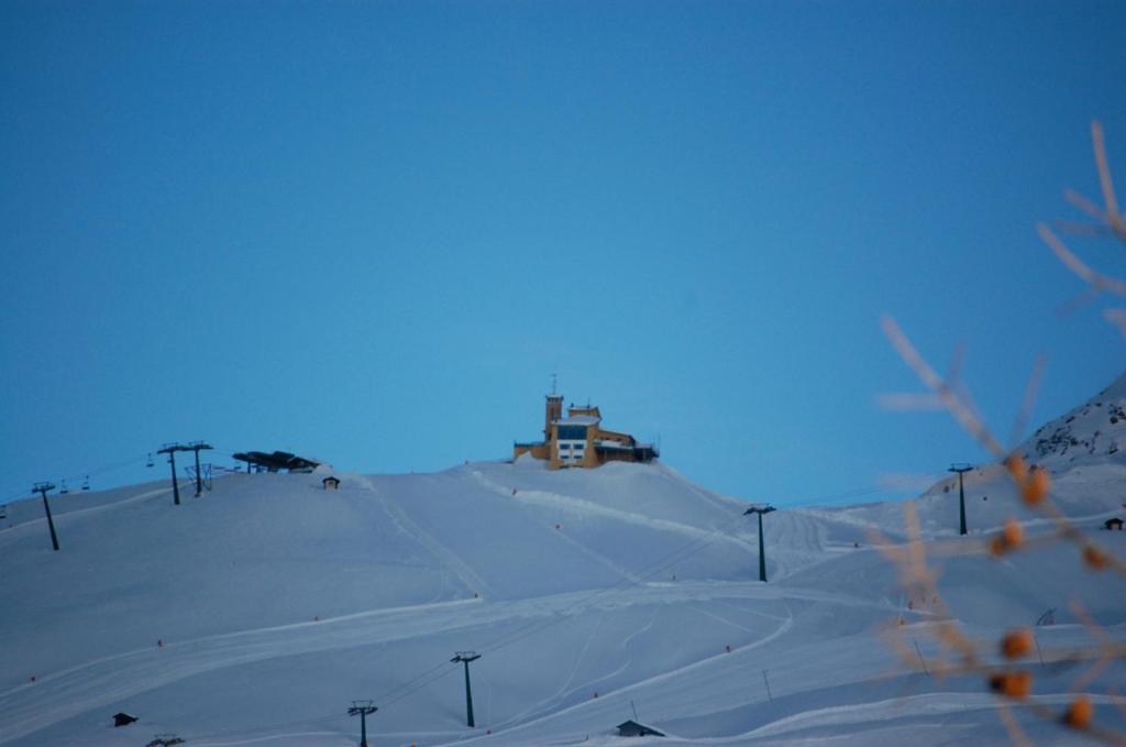 pokryte śniegiem wzgórze z domem na górze w obiekcie Tana Della Volpe w mieście Sestriere