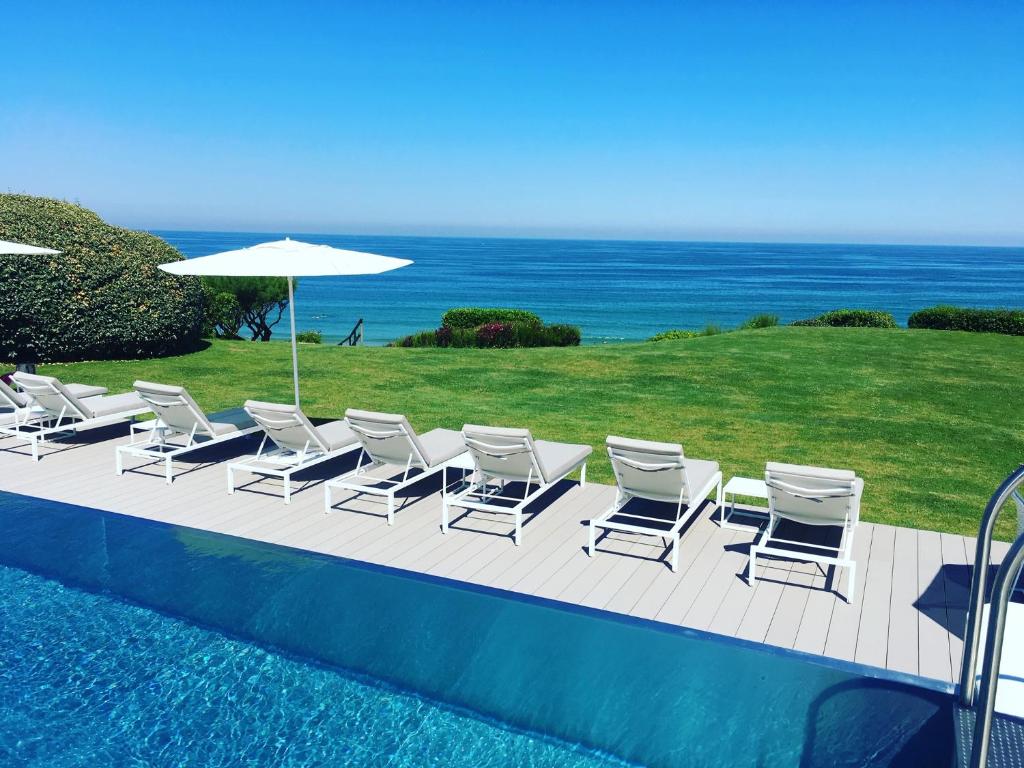 um grupo de cadeiras e um guarda-sol junto a uma piscina em Villa L'Arche em Bidart