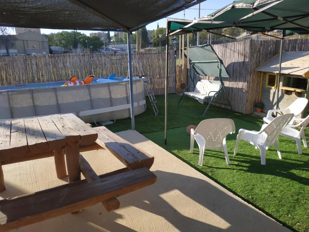 a picnic table and chairs under an umbrella in a backyard at Akhva Accommodation Unit-אחווה יחידת אירוח in Arad