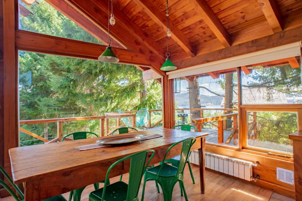 拉安戈斯圖拉鎮的住宿－科利納德爾曼薩諾山林小屋，一间带木桌和绿色椅子的用餐室