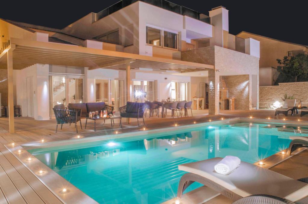 a swimming pool in front of a house at night at Villa Divino Afflante in Pirovac