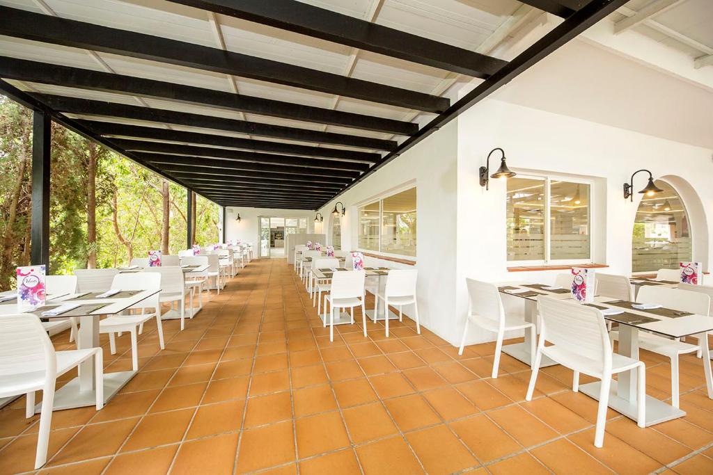a restaurant with white tables and white chairs at FERGUS Style Bahamas in Playa d'en Bossa