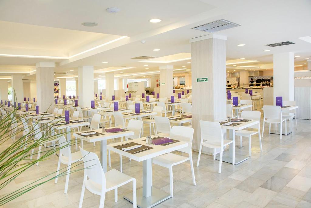 a restaurant with white tables and white chairs at FERGUS Style Bahamas in Playa d'en Bossa