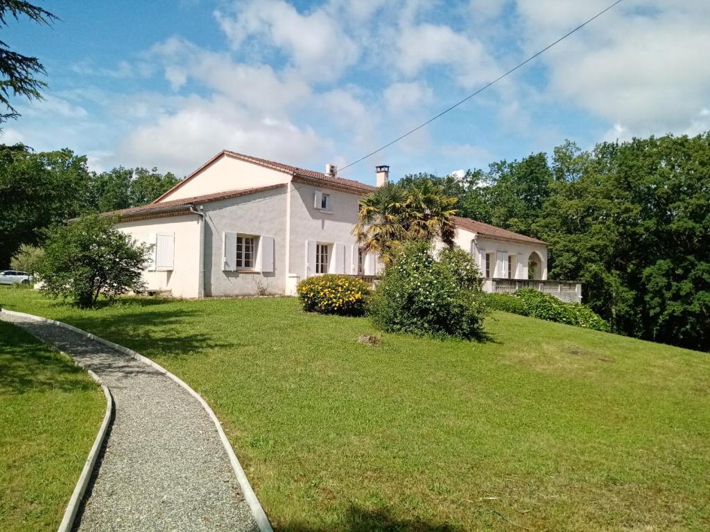 uma casa branca numa colina com um jardim de relva em LE CHEMINARD em Feugarolles