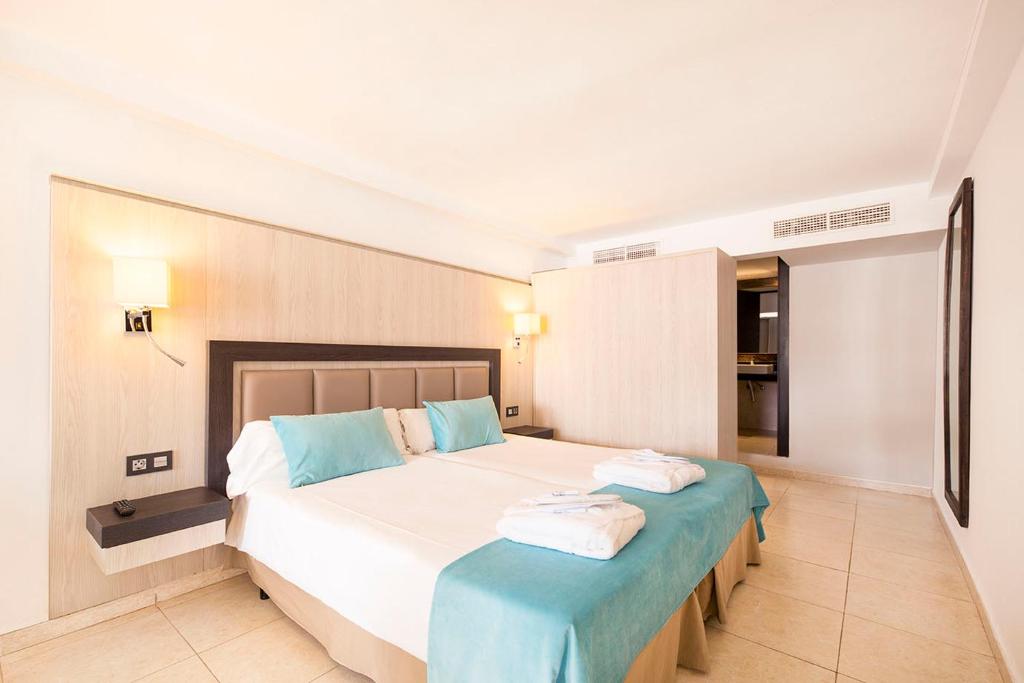 a bedroom with a large white bed with blue accents at FERGUS Style Bahamas in Playa d'en Bossa