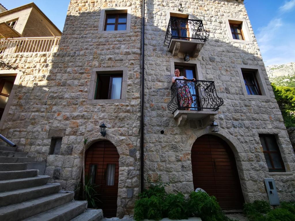 a woman on a balcony of a stone building at Apartments Linda in Drasnice