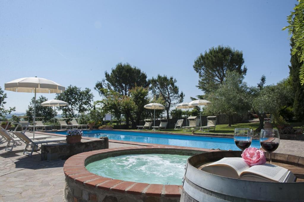 a pool with a table with wine glasses and a book at Agriturismo Lodolazzo in Cortona