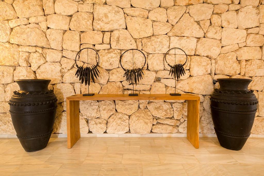 two black vases sitting on a table in front of a stone wall at FERGUS Style Bahamas in Playa d'en Bossa