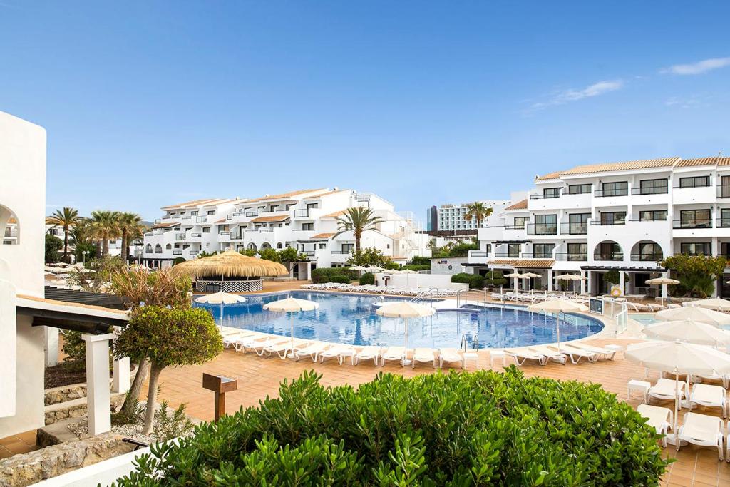 a swimming pool with umbrellas and chairs and buildings at FERGUS Style Bahamas in Playa d'en Bossa