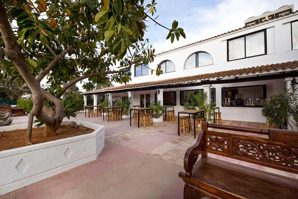 a patio with a tree and a bench in front of a building at FERGUS Style Bahamas in Playa d'en Bossa