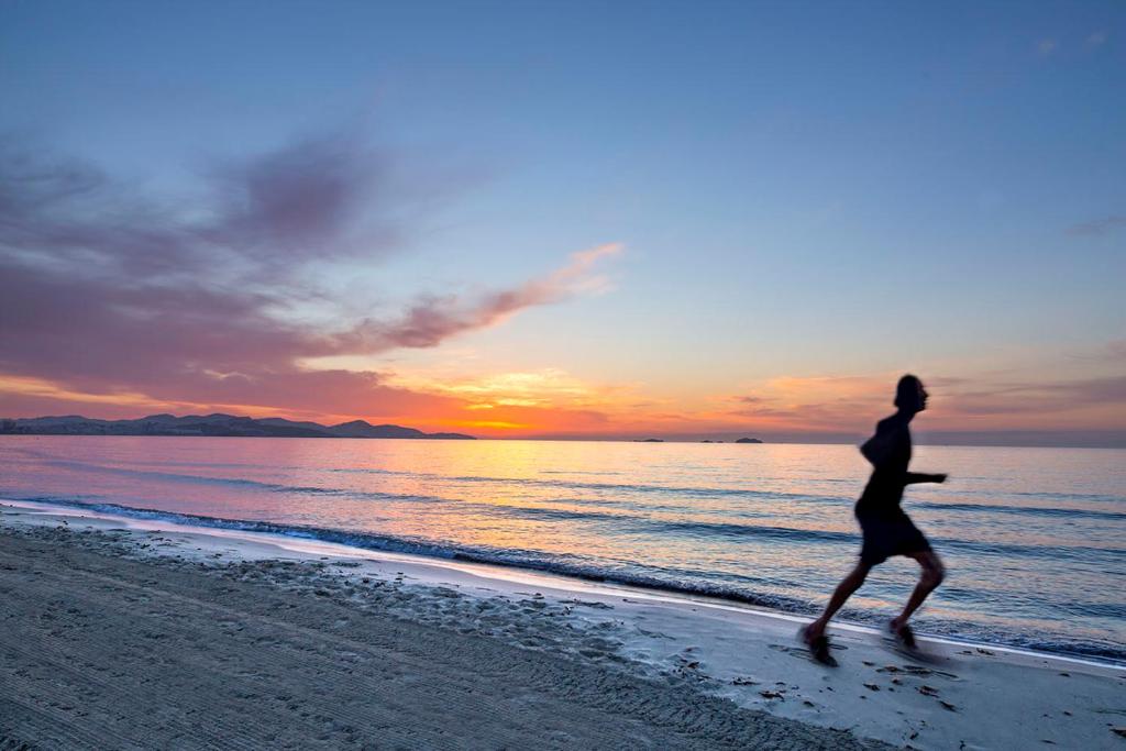 a man running on the beach at sunset at FERGUS Style Bahamas in Playa d'en Bossa