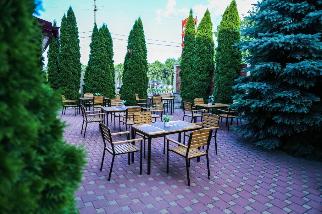 un patio con tavoli, sedie e alberi di Pensiunea Alexia a Iaşi