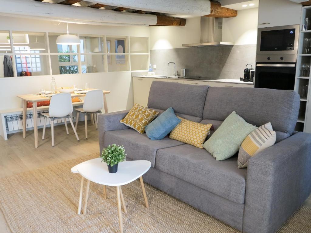 uma sala de estar com um sofá cinzento e uma cozinha em El Oasis de la Estafeta em Pamplona