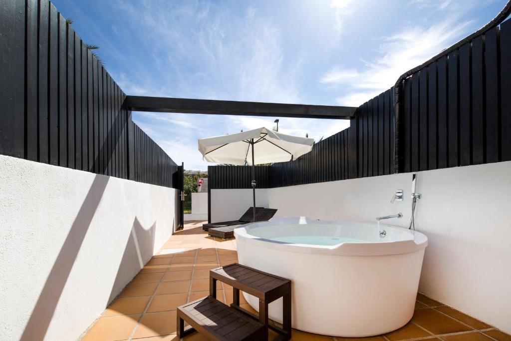 a bath tub on a balcony with an umbrella at FERGUS Style Bahamas in Playa d'en Bossa