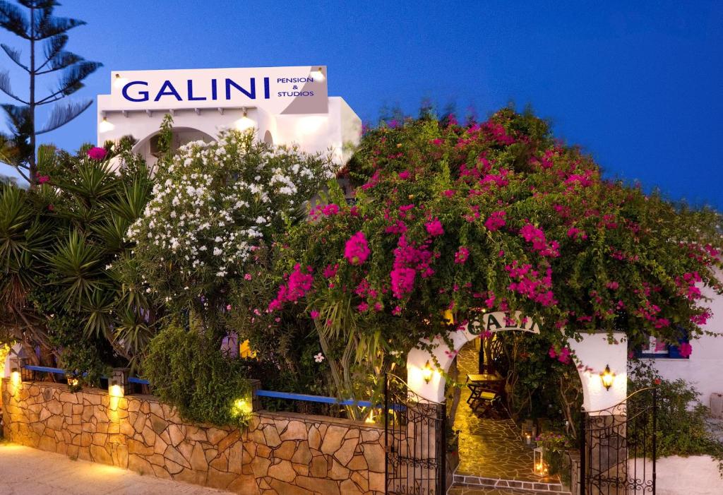 a building with pink flowers and a stone wall at Galini Pension in Ios Chora