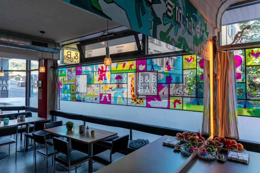 ein Restaurant mit Tischen und Stühlen und einer farbenfrohen Wand in der Unterkunft Bettstatt-Neustadt in Luzern