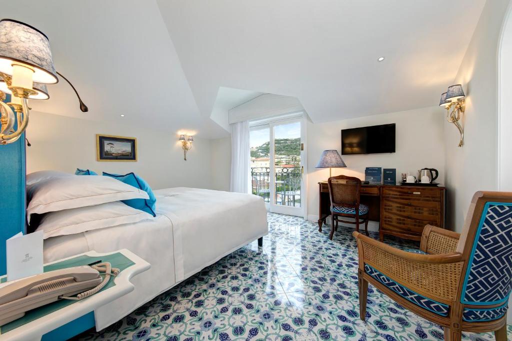 a bedroom with a bed and a desk and a chair at Grand Hotel Ambasciatori in Sorrento