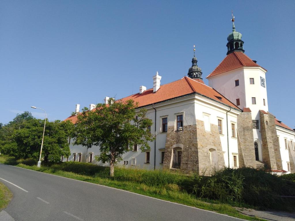 un antiguo edificio con una torre al lado de una carretera en gemuetliche unterkunft bei prag en Smečno