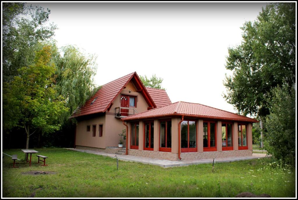 une petite maison avec un toit rouge dans un champ dans l'établissement Számadó Vendégház, à Poroszló