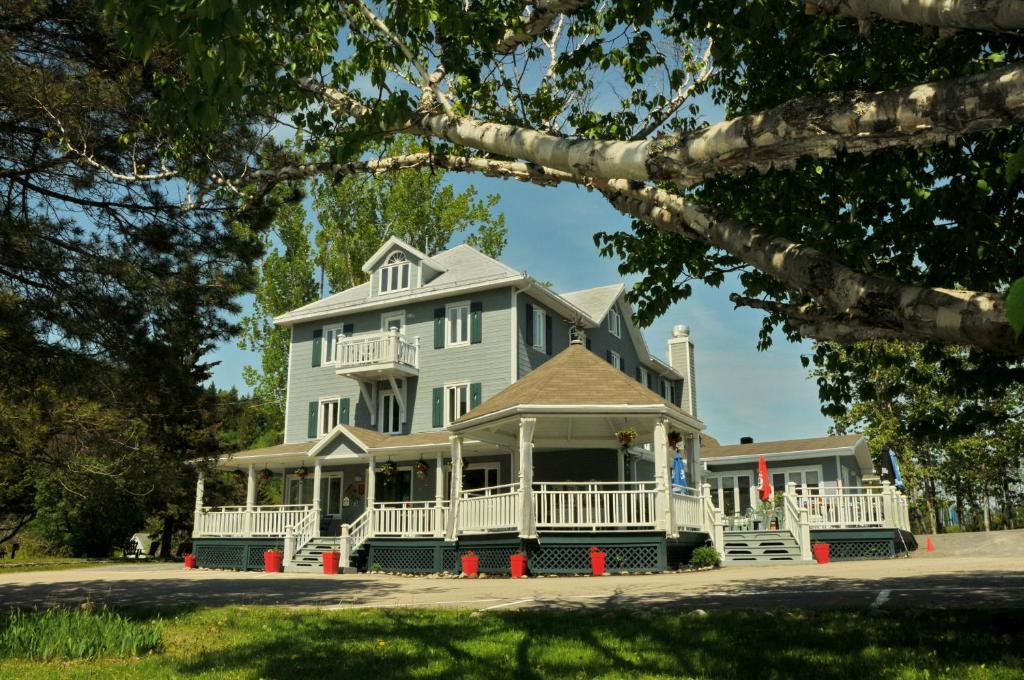 une grande maison blanche avec une grande véranda dans l'établissement Auberge Beausejour, aux Éboulements