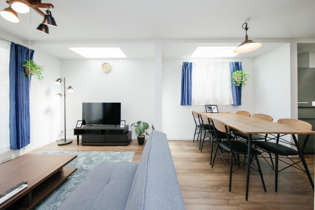 ein Wohnzimmer mit Tisch und Stühlen und einem Fernseher in der Unterkunft Higashi Rokugou WHITE / Vacation STAY 4276 in Tokio