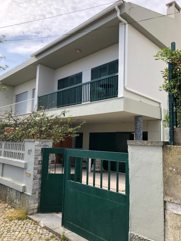 a house with a green gate in front of it at Caparica Beach House Holiday Home in Costa da Caparica