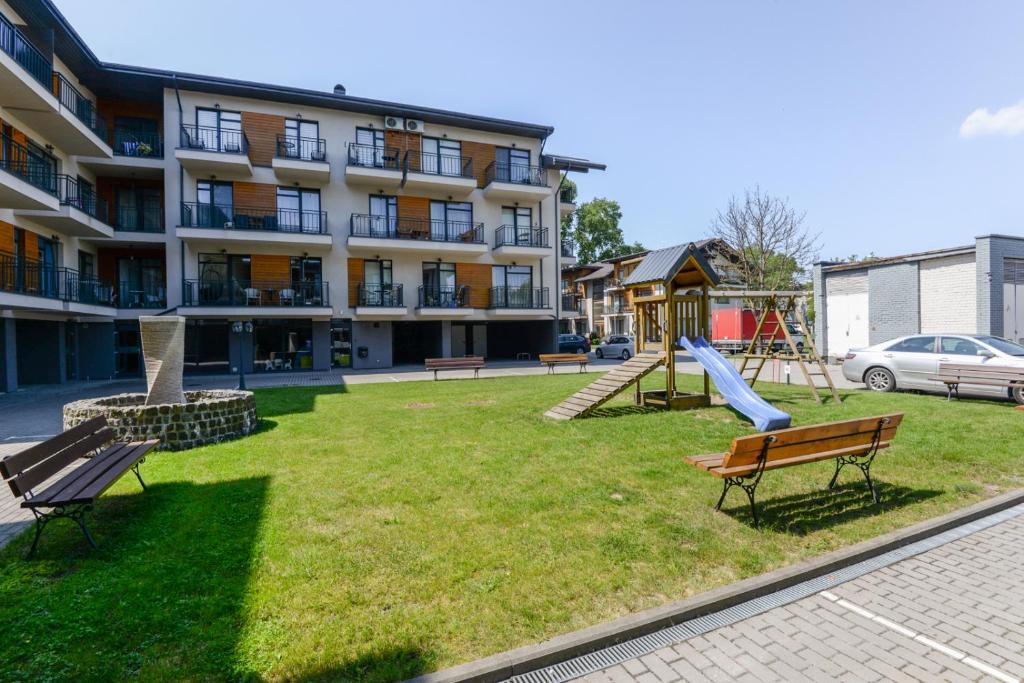 a park with benches and a playground in front of a building at For you in Palanga