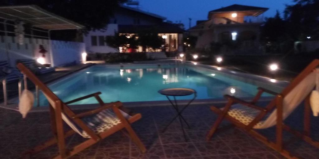 a swimming pool at night with two chairs and a table at Dalyan Holiday Hotel in Ortaca